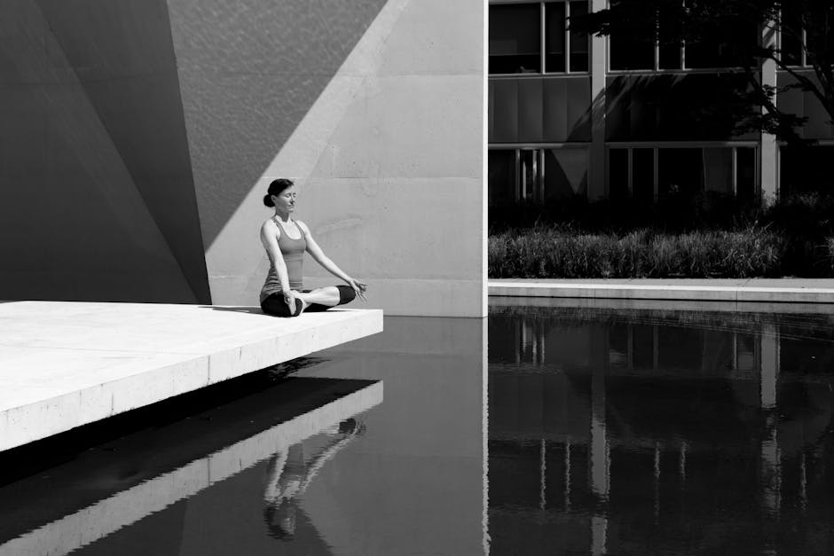 A woman meditating by a poolside, reflecting tranquility and focus in a minimalist setting